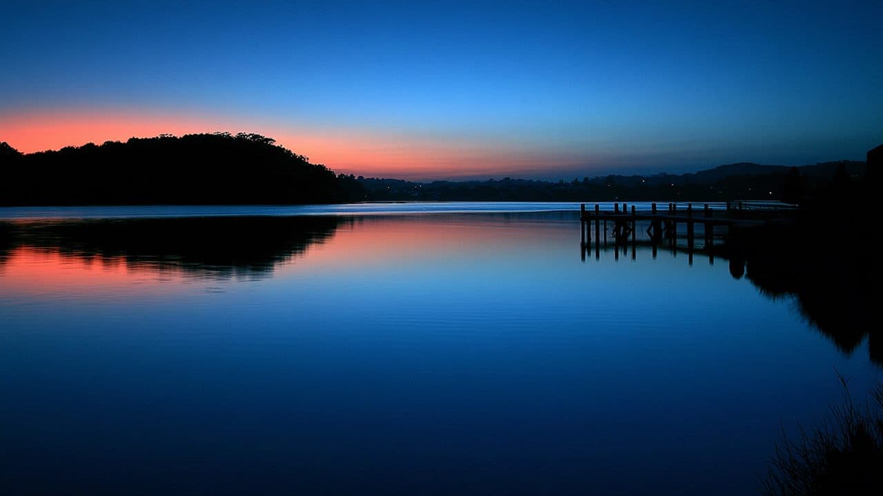 The Narooma coastline at dusk, red sunset light meeting blue twilight over the water